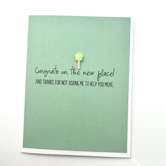 Green card with text 'Congrats on the new place' and a small decorative item on a white background