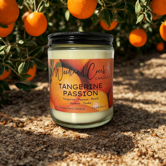 Candle jar labeled 'Tangerine Passion' by Woodland Creek Candles with tangerines in the background.